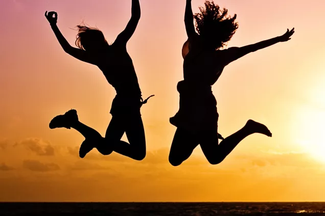 Two persons jumping with sunset in the background