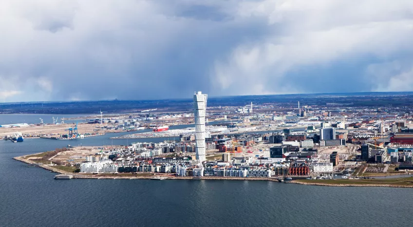 A drone picture of Malmö west harbour taken from the sea, with the Turning Torso prominent in the centre. 