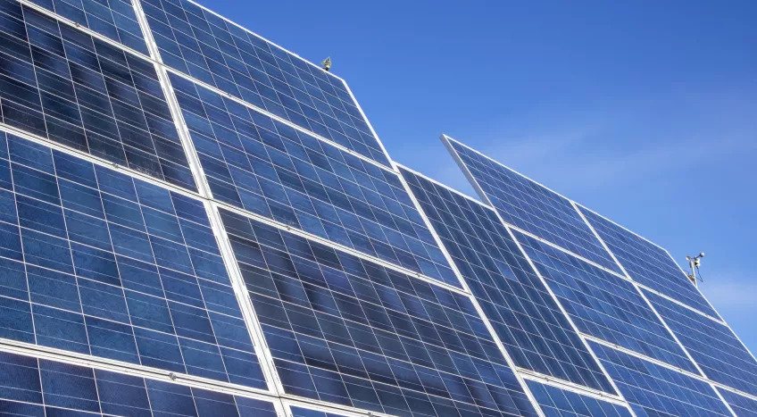 A picture of solare panels against a blue sky, as seen from below 