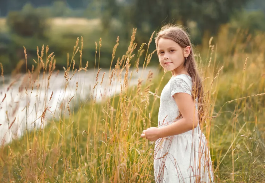 Girl standing in the midst of a grass field