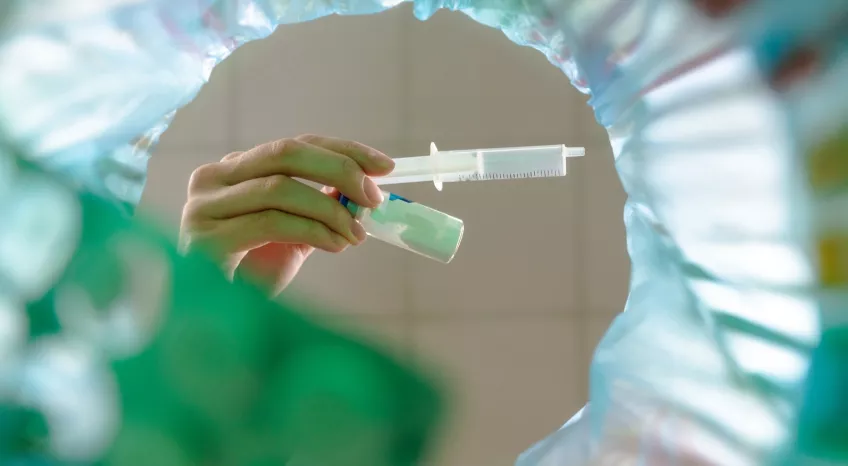 A picture taken from below of a hand holding a syringe in a hospital setting 